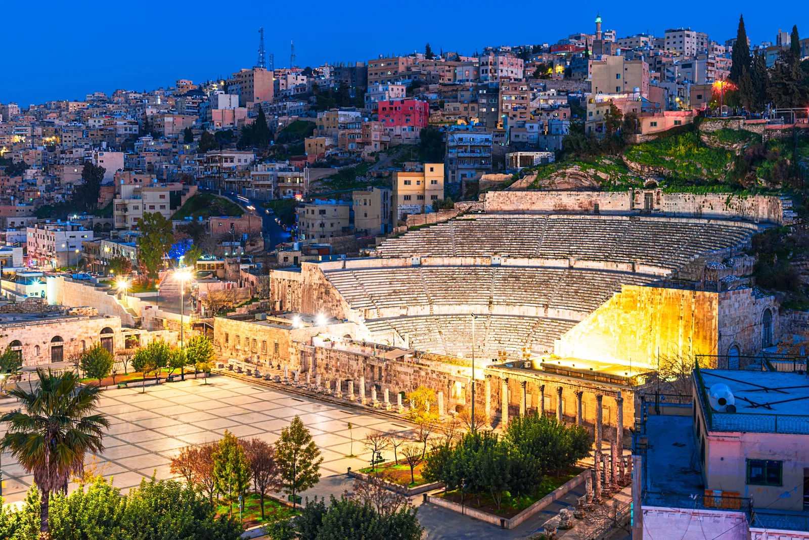 Amman — The theatre after sunset Illuminated Roman Theatre beneath the hillside buildings of Amman at dusk